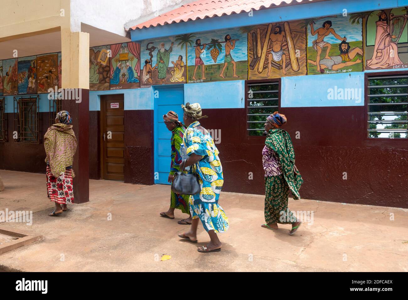 Togo, Togoville, women walking in front of the frescoes of Notre dame du lac cathedral Stock Photo