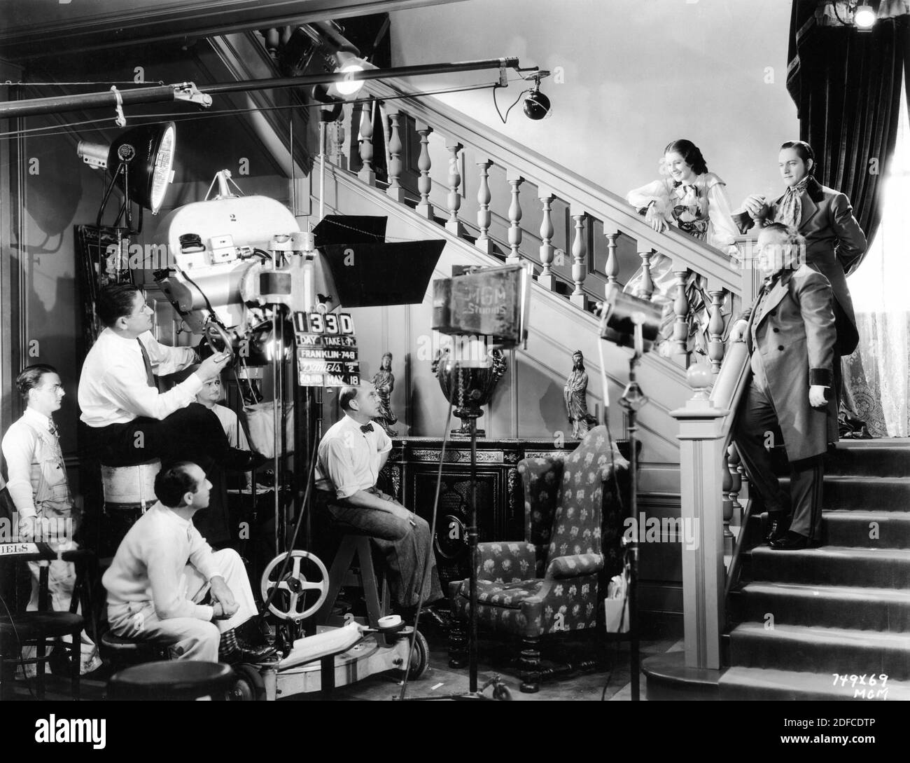 Cinematographer WILLIAM H. DANIELS Director SIDNEY FRANKLIN and Movie Crew with NORMA SHEARER FREDRIC MARCH and CHARLES LAUGHTON on set candid during filming of THE BARRETTS OF WIMPOLE STREET 1934 director SIDNEY FRANKLIN play Rudolph Besier Metro Goldwyn Mayer Stock Photo