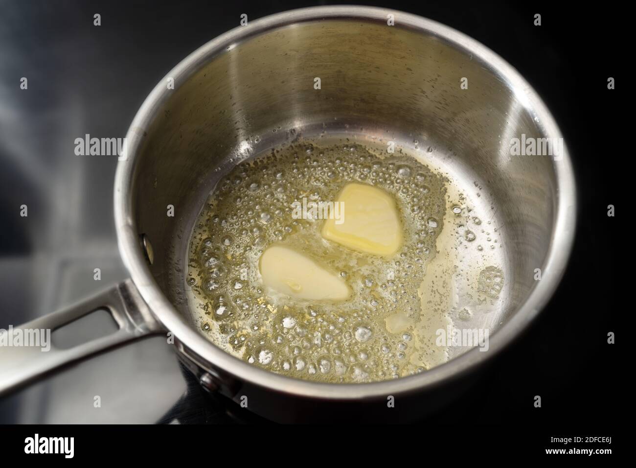 Melting butter in a stainless steel saucepan on the black stove