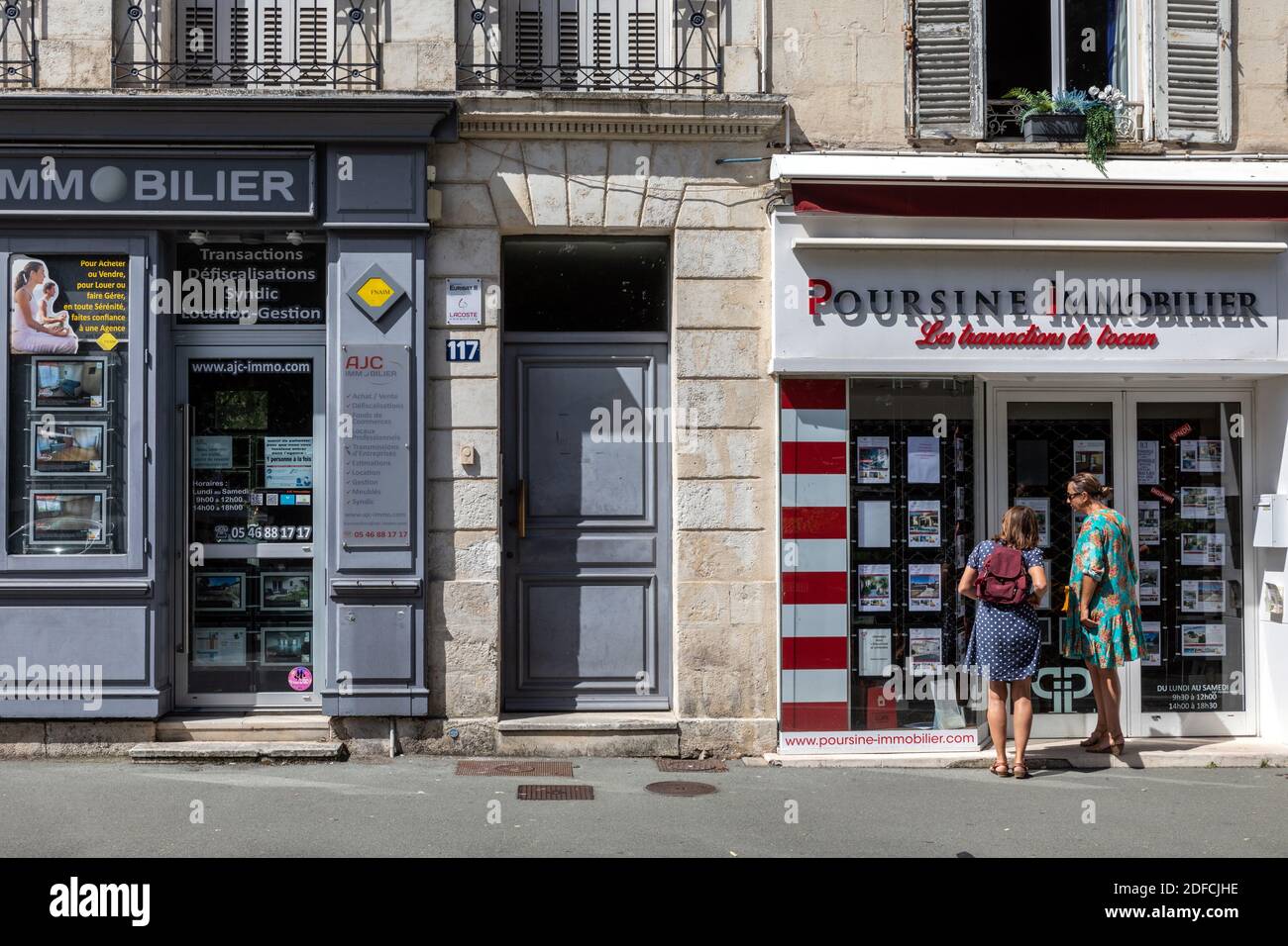 PASSER-BY IN FRONT OF THE STOREFRONT WITH REAL ESTATE ADS, REAL ESTATE AGENCY FOR RENTALS, SALES AND MANAGEMENT, ROCHEFORT, CHARENTE-MARITIME, FRANCE Stock Photo