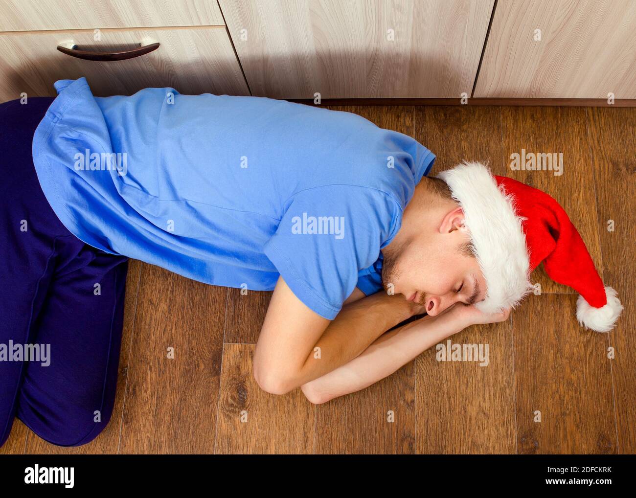 Young Man in Santa Hat sleeping on the Floor at the Home Stock Photo