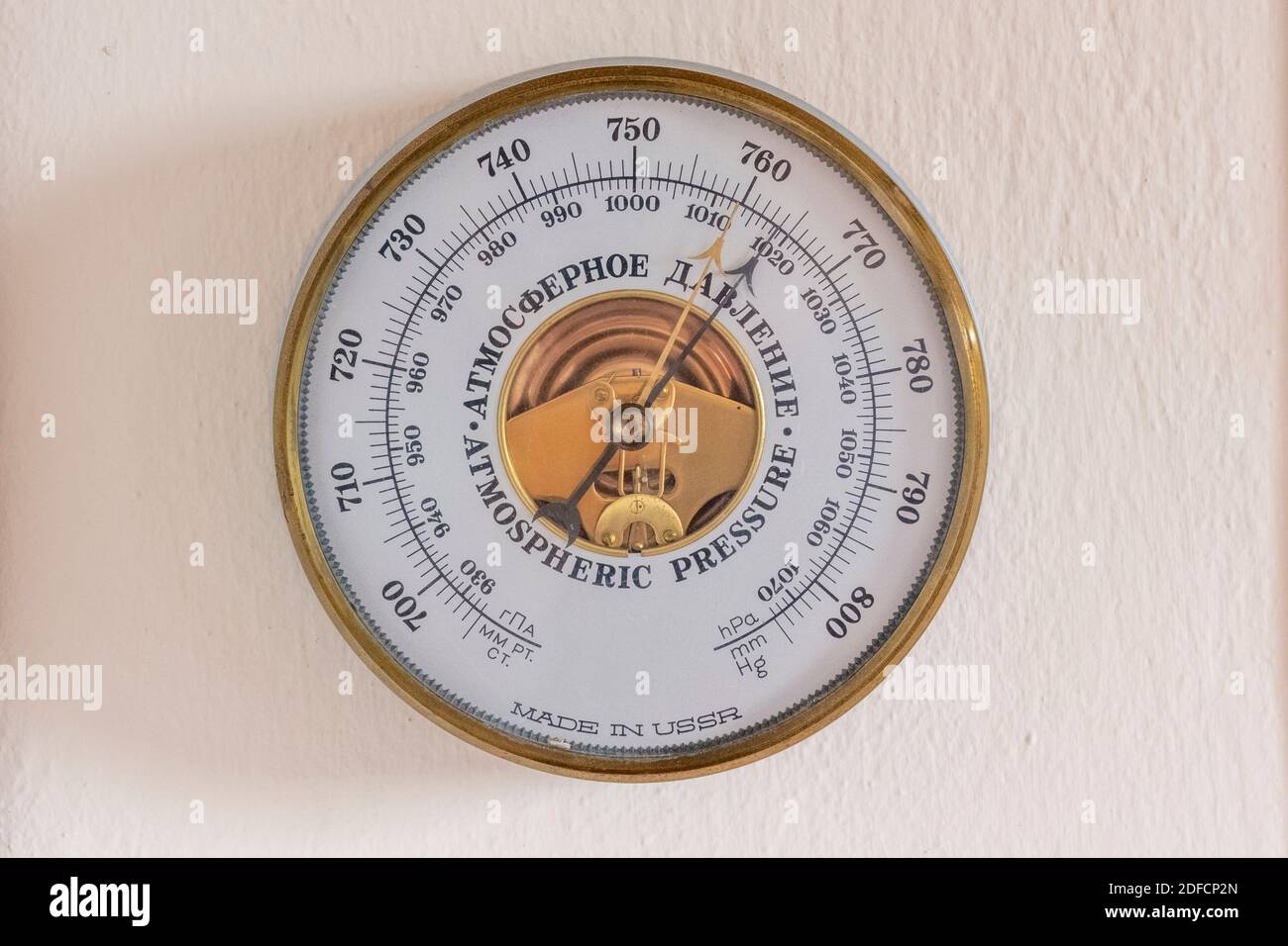 A golden framed, USSR made, atmospheric pressure barometer hanging on a