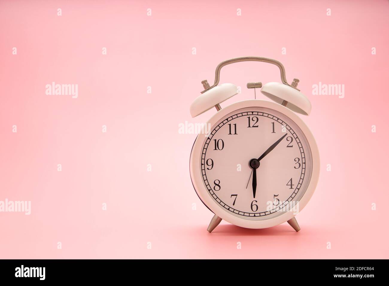 Close up a white clock on a pink background. Concept image. Stock Photo