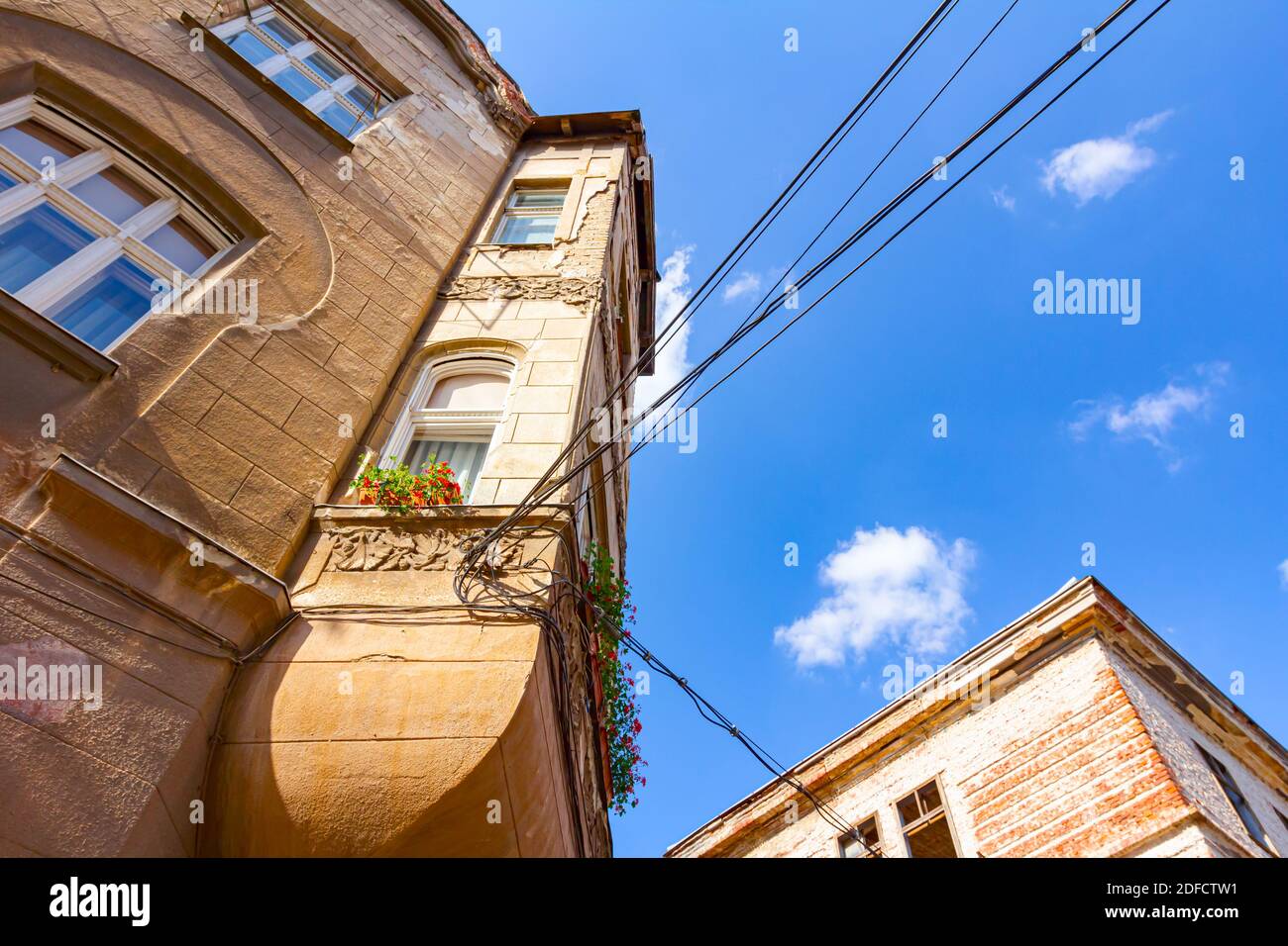 Bottom side view on damaged facade of building with flowerpots on the ...