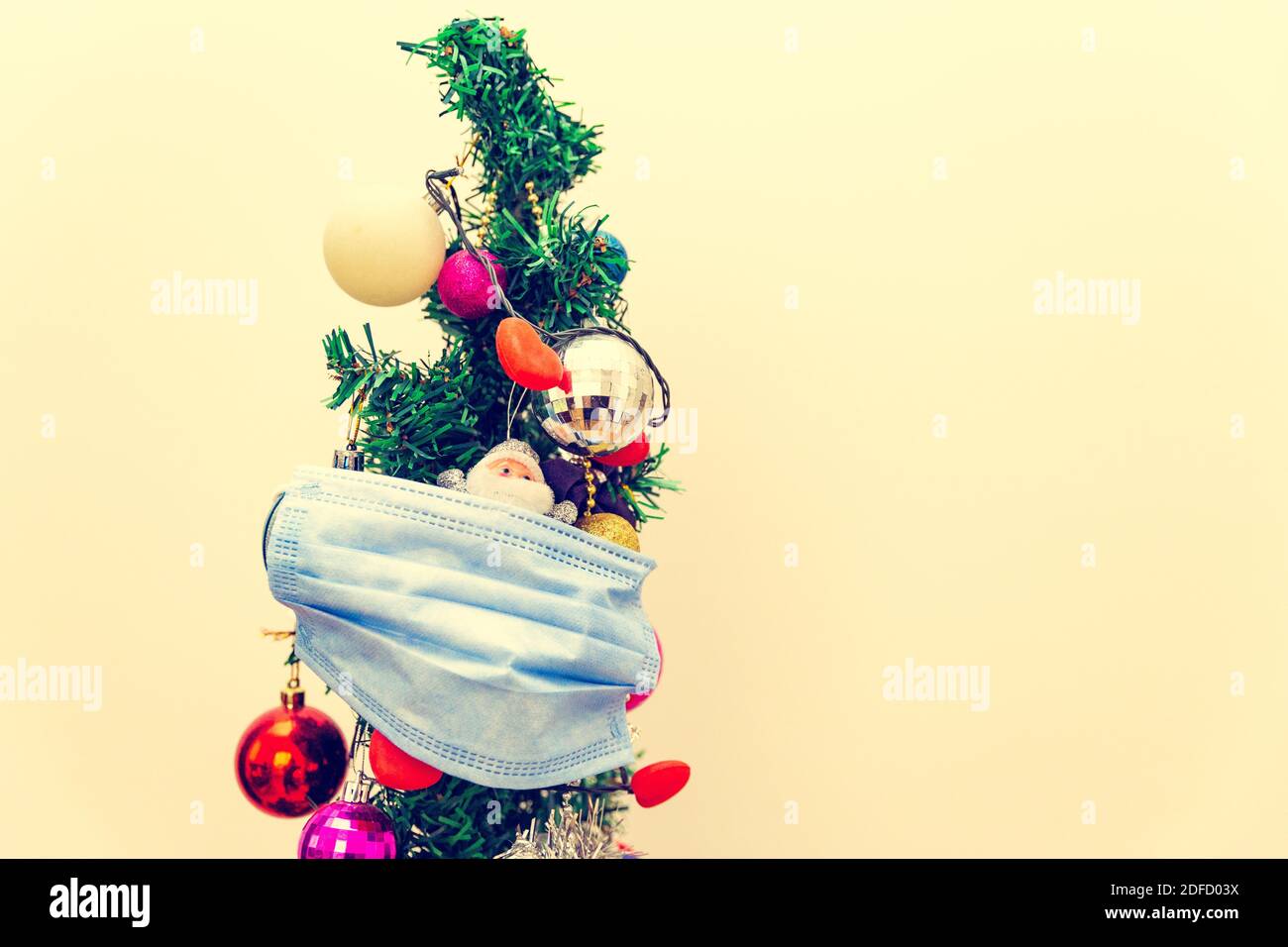 Merry Christmas in the new Covid-19. Front view of a Christmas tree with medical face mask. The concept of the new year during the pandemic. Stock Photo