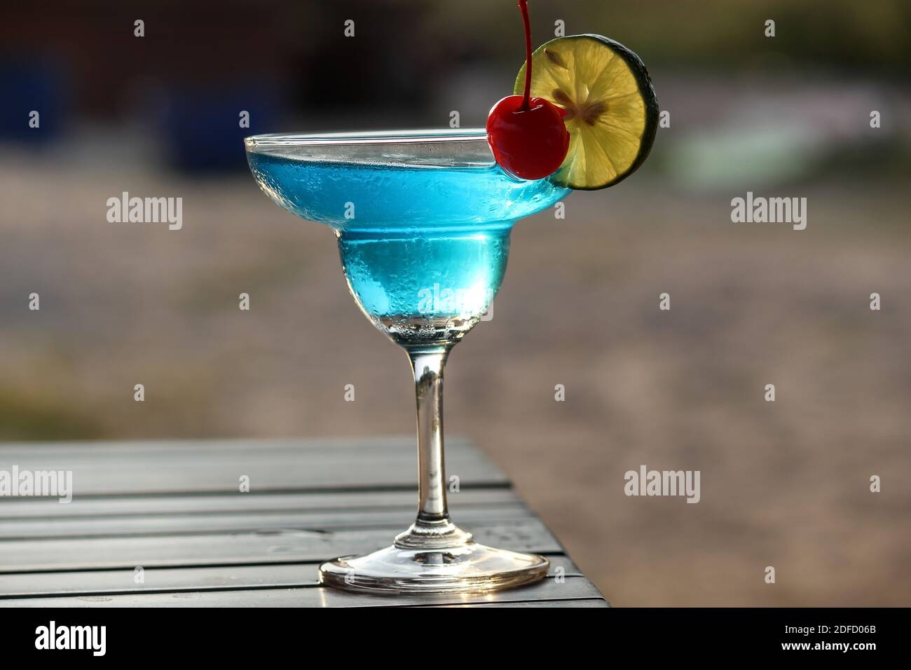 Juice that may contain alcohol to add flavor in a clear, round glass with a thin slice of kaffir lime garnish with a cherry. Stock Photo