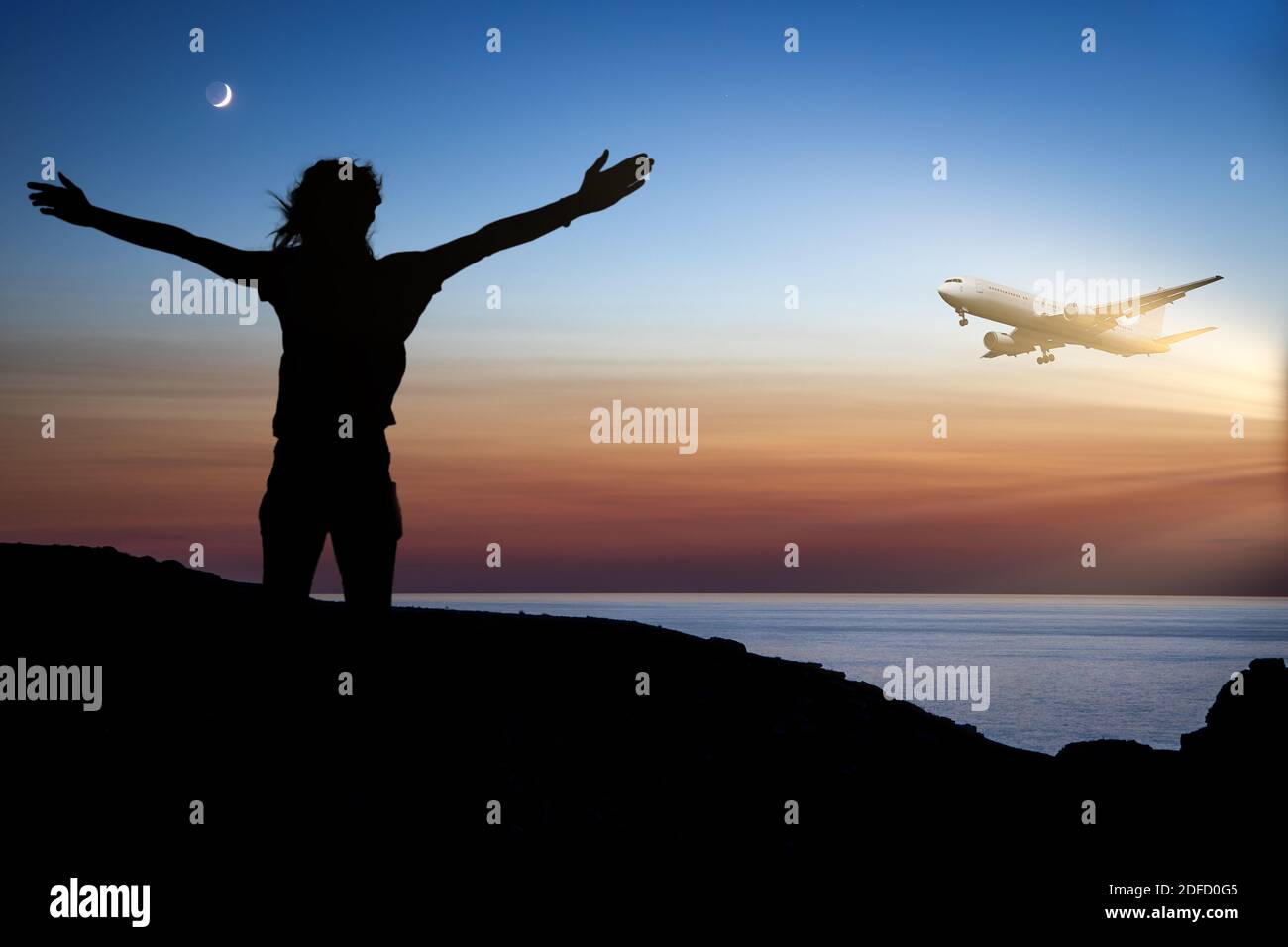 Woman on the island waving her arms to flying plane during sunset Stock Photo