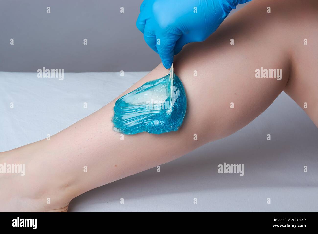 the procedure shugaring legs.the application of blue sugar paste.depilation in the salon Stock Photo