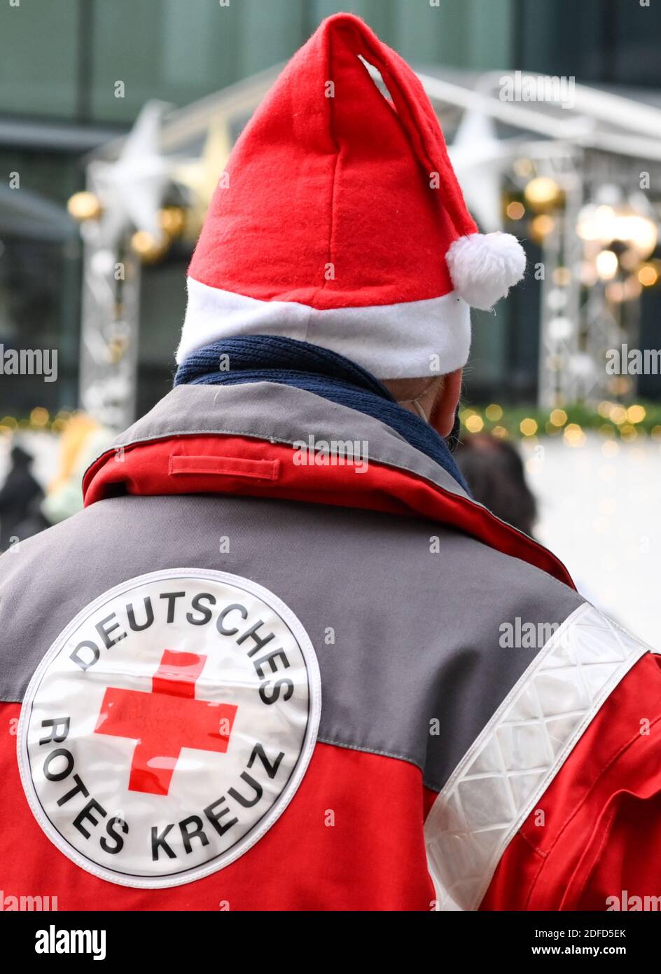 Berlin, Germany. 04th Dec, 2020. An employee of the German Red Cross stands  with a Santa Claus cap at the charity Christmas market of Kranzler Eck on  Kurfürstendamm. Non-profit institutions present themselves