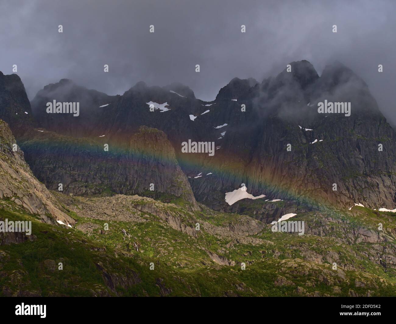 Stunning view of strong colorful rainbow on the coast of Austvågøya island, Lofoten, Norway on Raftsundet strait with majestic rugged mountain range. Stock Photo