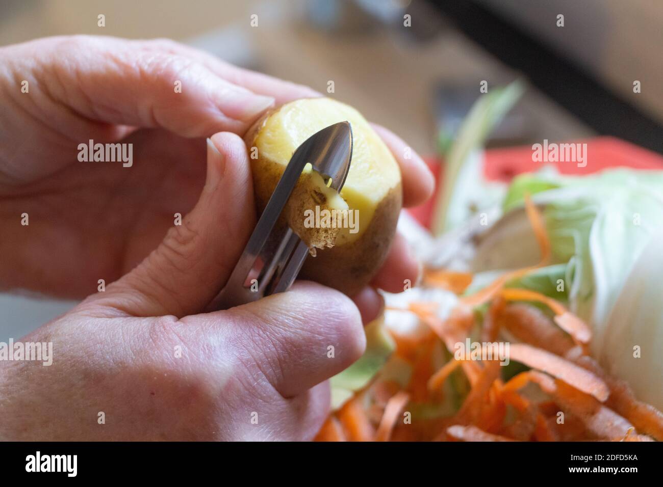 To peel a potato with a peeler in a kitchen Stock Photo Alamy