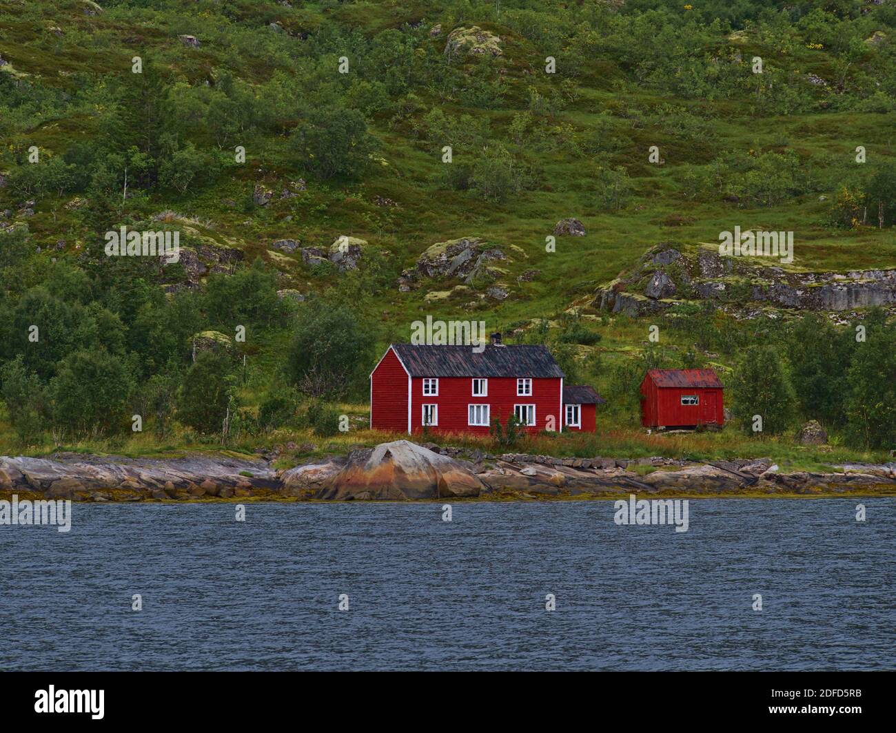 Traditional Norwegian wooden house with red painted facade located on rocky shore of Raftsundet strait on Austvågøya island, Lofoten, Norway. Stock Photo