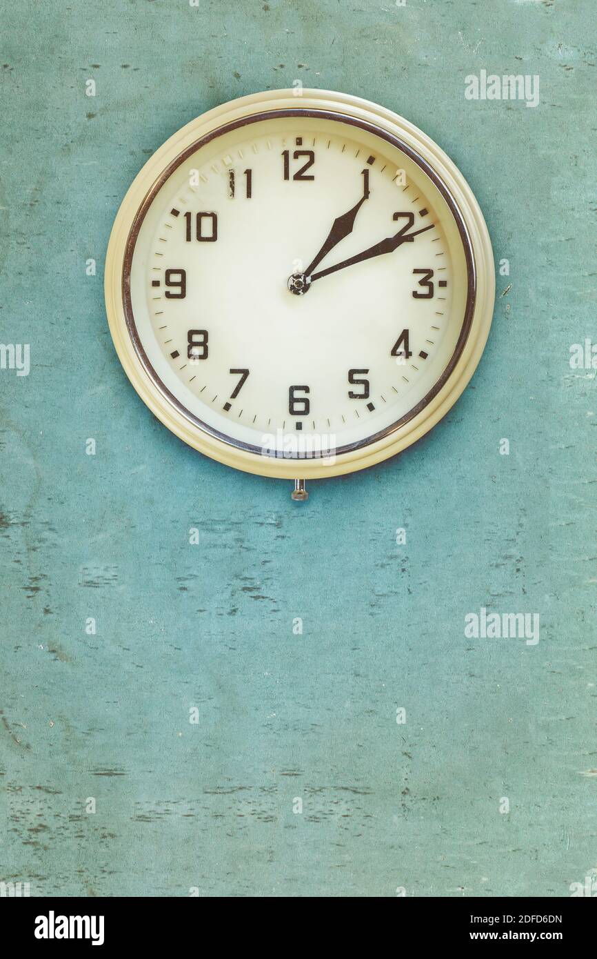 Vintage mid twentieth century plastic electric clock on a blue weathered wall Stock Photo