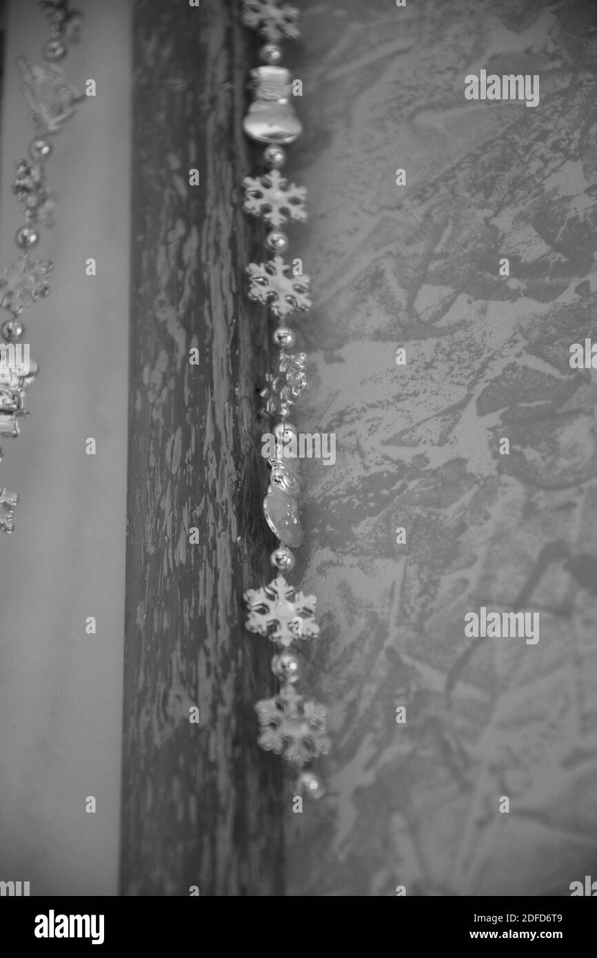 Black and white photo of garland with beads and snowflakes with blurred background and copy space for Christmas Stock Photo