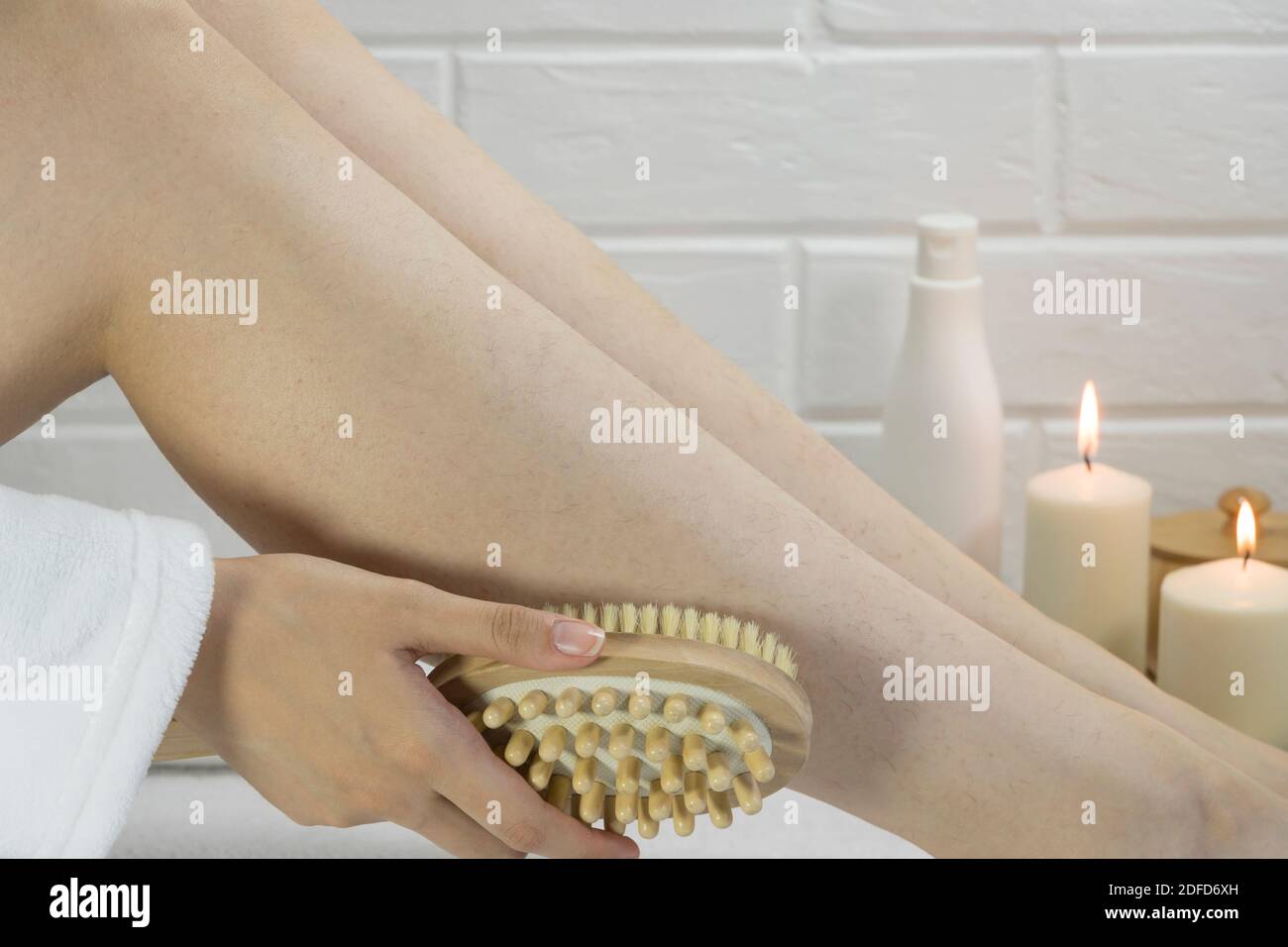Dry brush massage. Preparing the skin for epilation. Exfoliation with a natural bristle brush. Strawberry legs, keratosis. Home skin and body care. SP Stock Photo