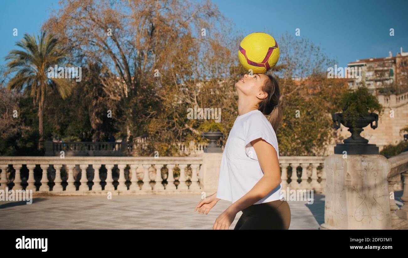 Pretty sporty girl practicing football skills outdoor. Confident