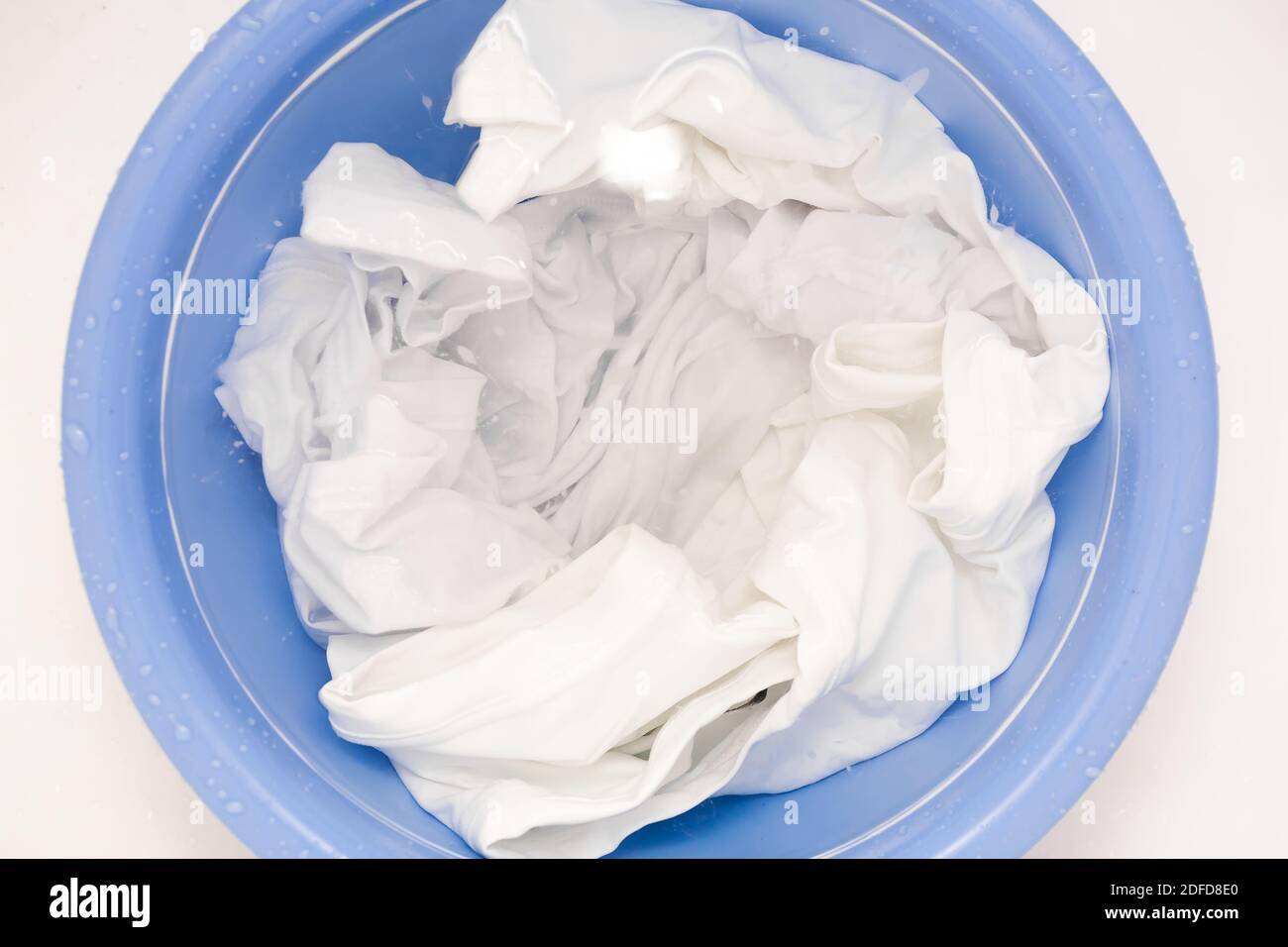 A laundry concept with soak white clothes close up in blue bowl