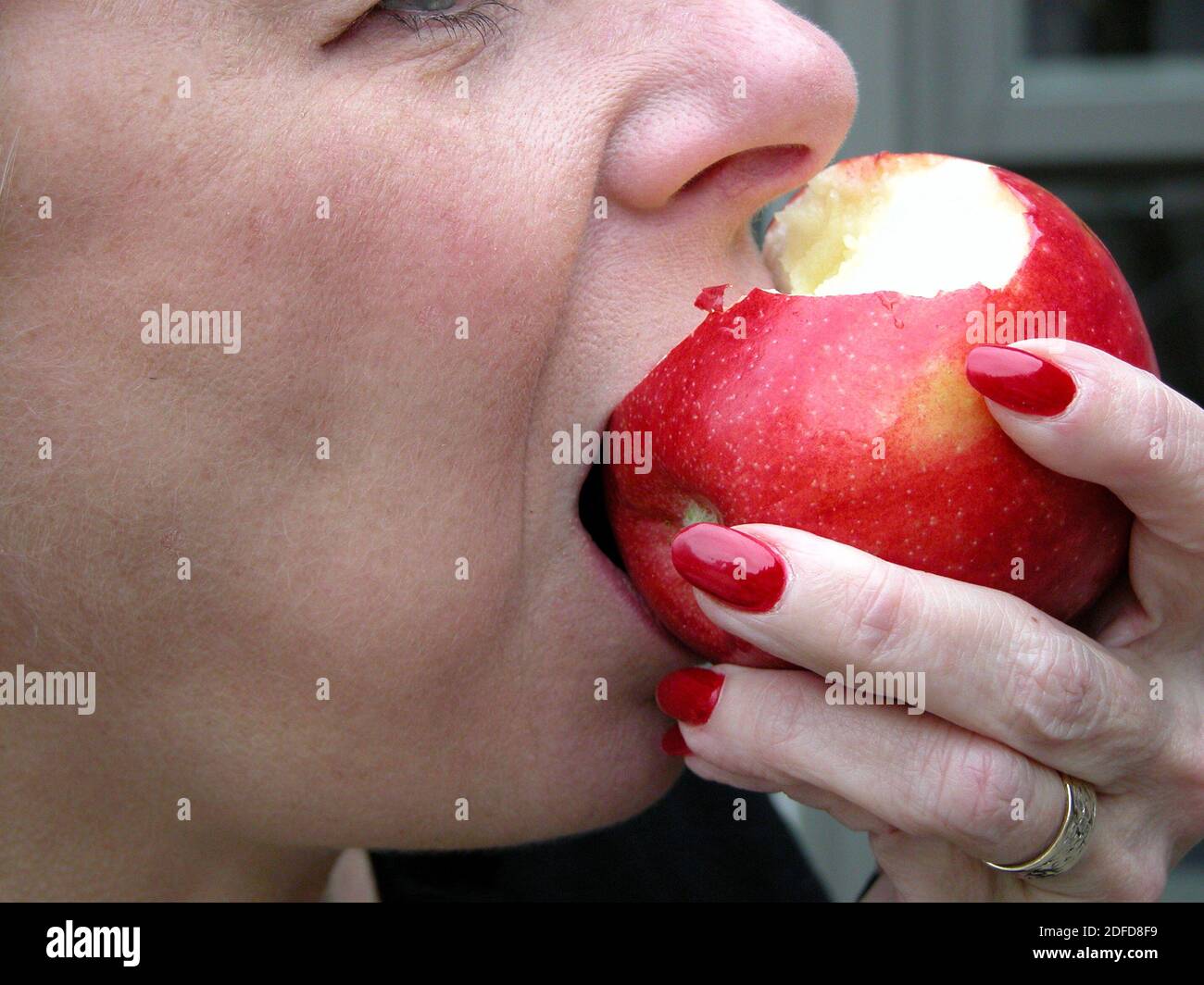Woman taking a bite from a red delicious apple Stock Photo