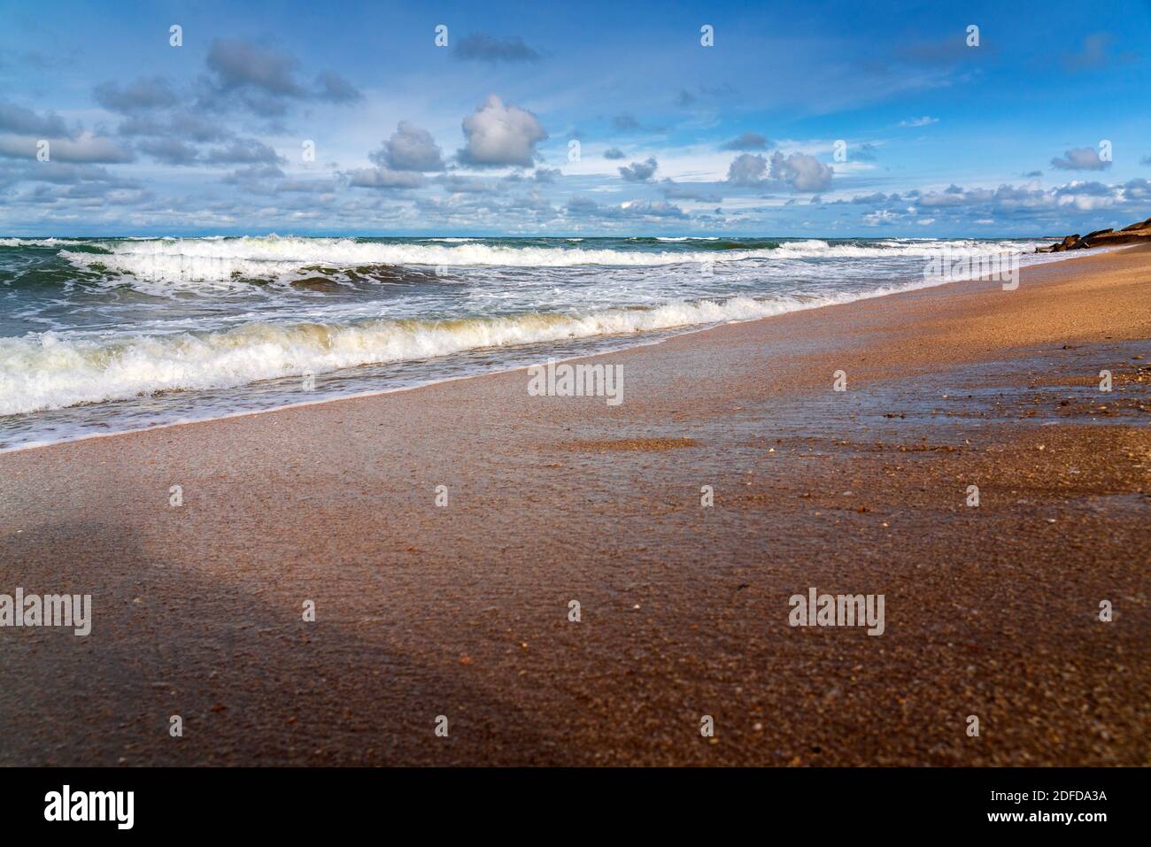 Sandy beach, small waves and blue sky with clouds Stock Photo - Alamy