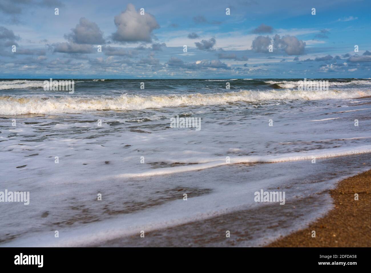 Sandy beach, small waves and blue sky with clouds Stock Photo - Alamy
