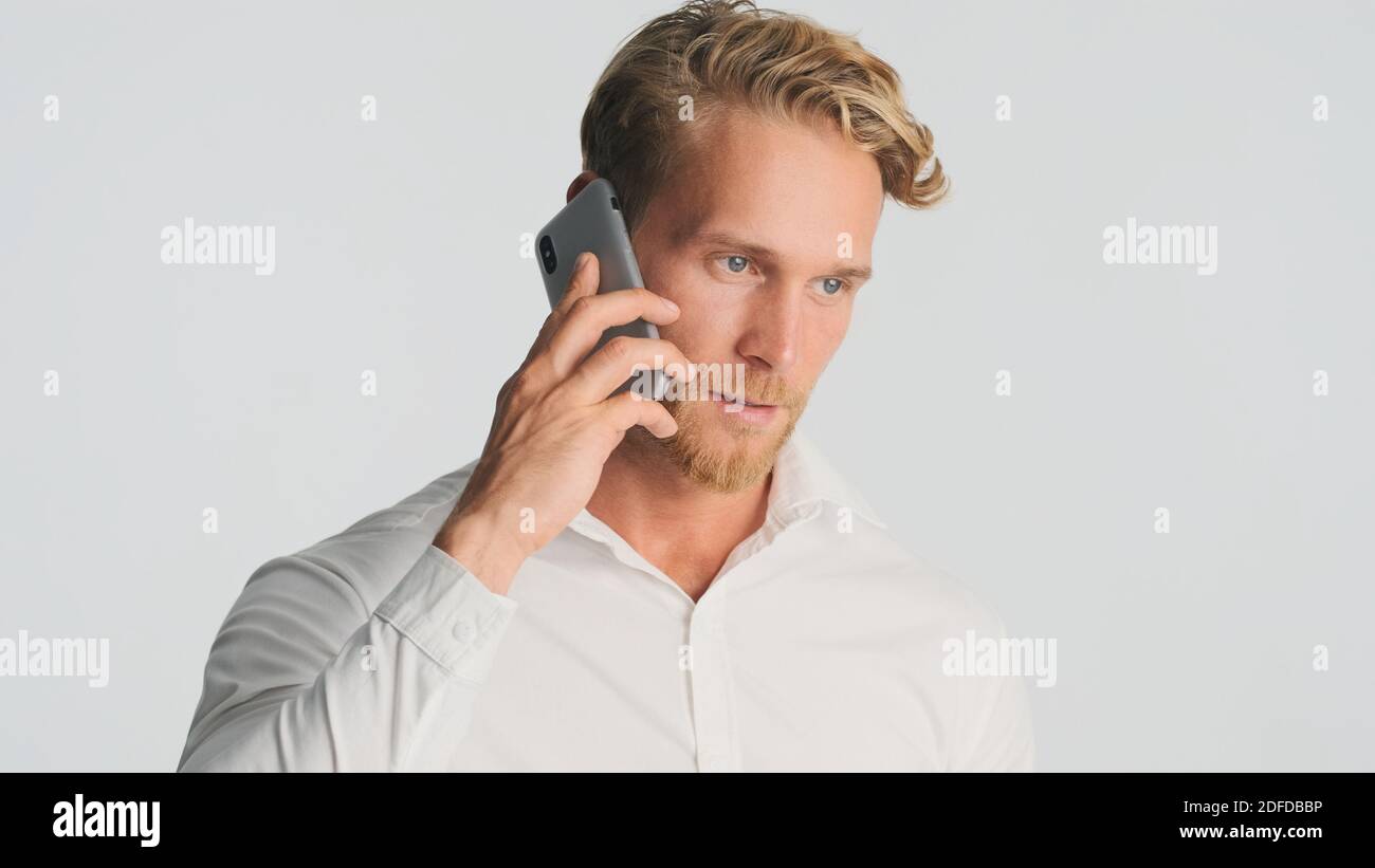 Handsome bearded man in shirt talking with business partner on smartphone over white background. Business talk. Modern technology Stock Photo