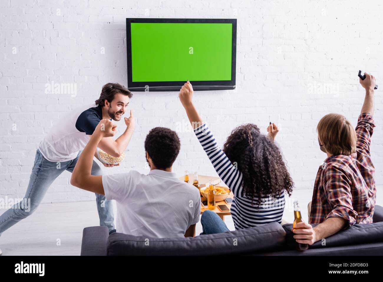 beard hot Intolerable excited man pointing at lcd tv on wall near multicultural friends watching  sport competition Stock Photo - Alamy