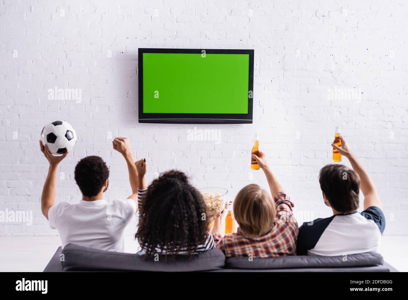 back view of multicultural football fans showing win gesture while
