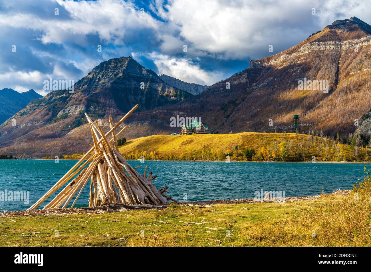 Driftwood Beach, Middle Waterton Lake lakeshore in autumn foliage season morning. Blue sky, white clouds over mountains in the background. Landmarks i Stock Photo