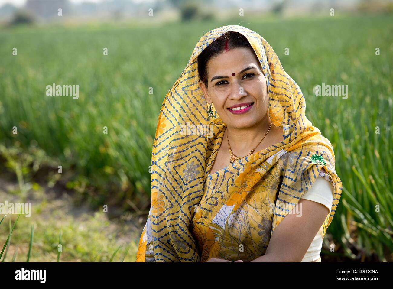 Smiling Indian woman farm owner standing in agricultural field Stock