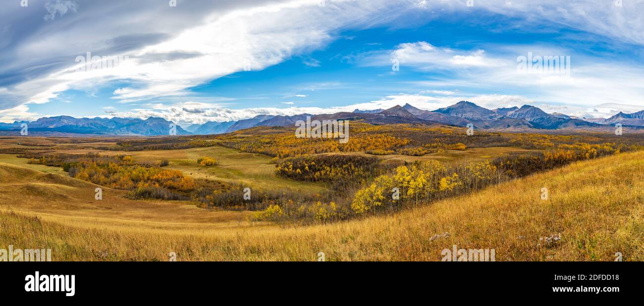 Vast prairie and forest in beautiful autumn. Sunlight passing blue sky and clouds on mountains. Fall color landscape background. Waterton Scenic Spot, Stock Photo
