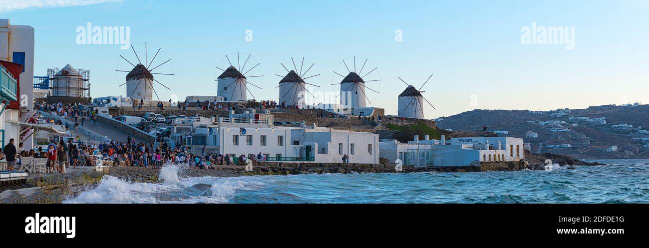 Mykonos, Greece - 10 September 2019: time lapse, tourists near "Little Venice" admire the sunset. In the background the panoramic windmills. Stock Photo