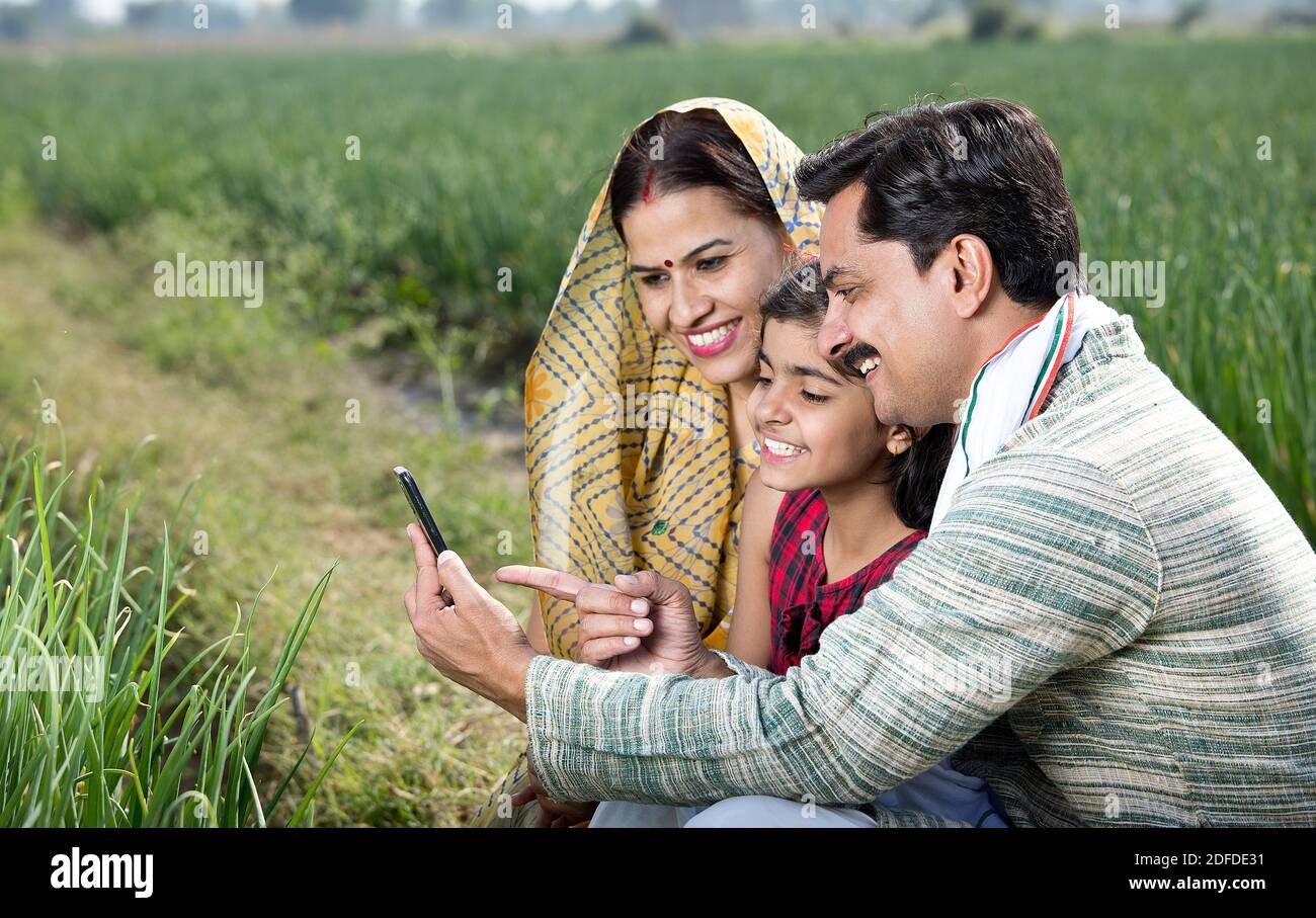 Happy family of farmer in agricultural field using phone Stock Photo ...