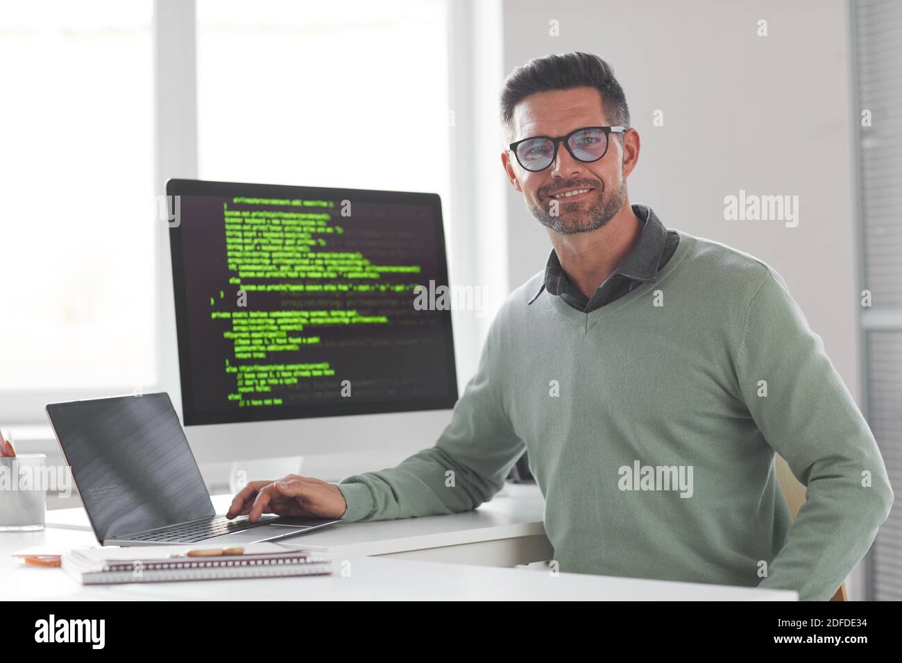 Portrait of mature computer programmer in eyeglasses looking at camera while developing new computer system Stock Photo