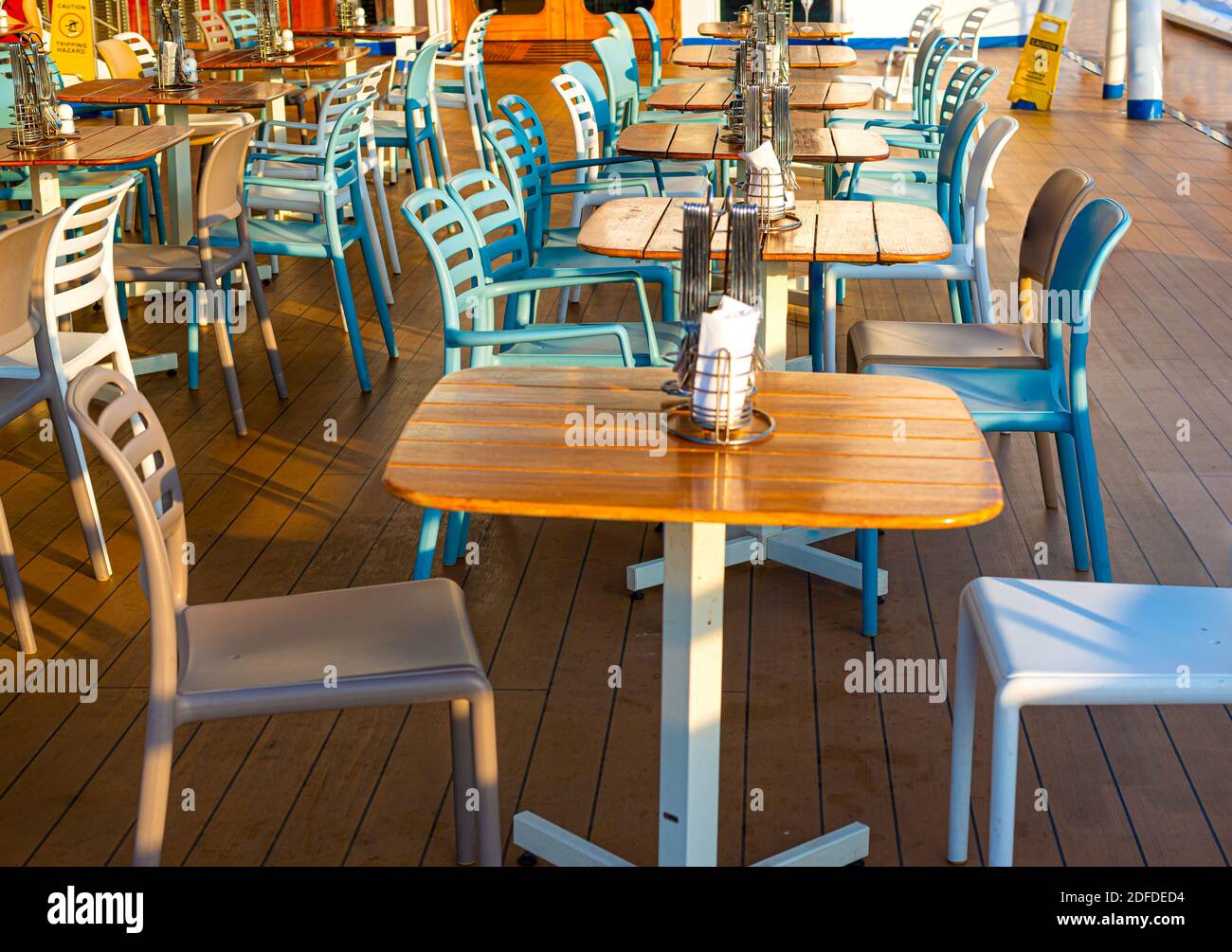 Wooden deck chairs and tables on the outdoor deck of a cruise ship