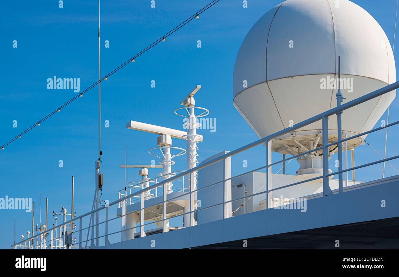 White color satellite antenna of cargo a ship and sun loungers on deck of cruise ship Stock Photo