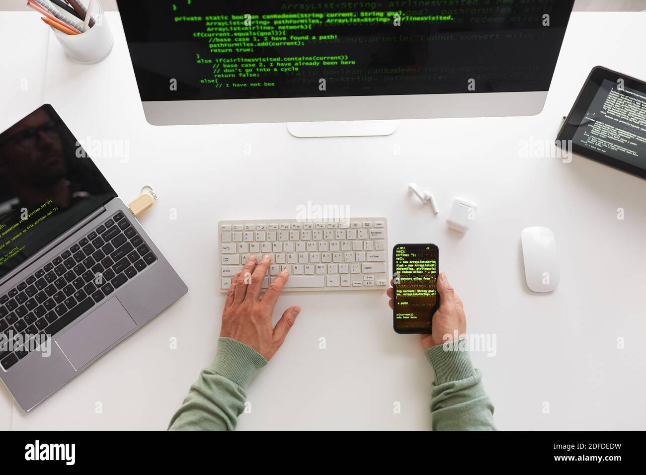 High angle view of programmer sitting at the table using computer laptop and mobile phone programming website design Stock Photo