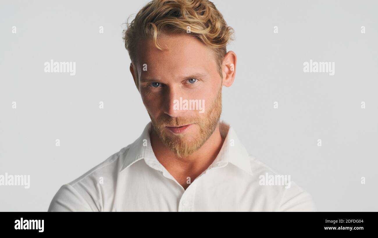 Young handsome bearded businessman in shirt looking serious on camera isolated on white background. Confident man in shirt Stock Photo