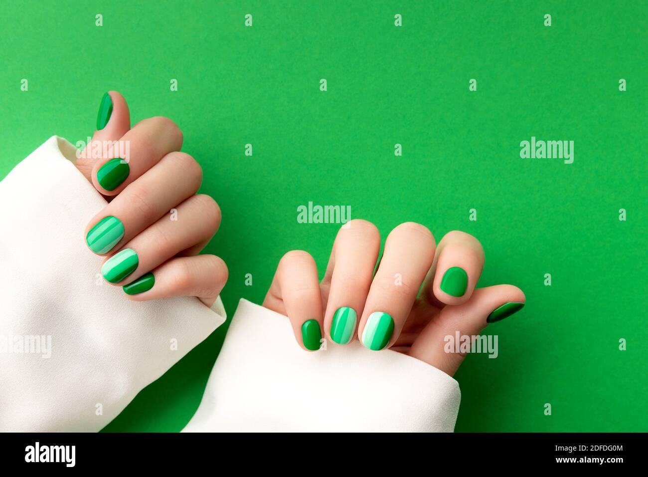 Beautiful groomed woman's hands with spring summer nail design on green  background Stock Photo - Alamy