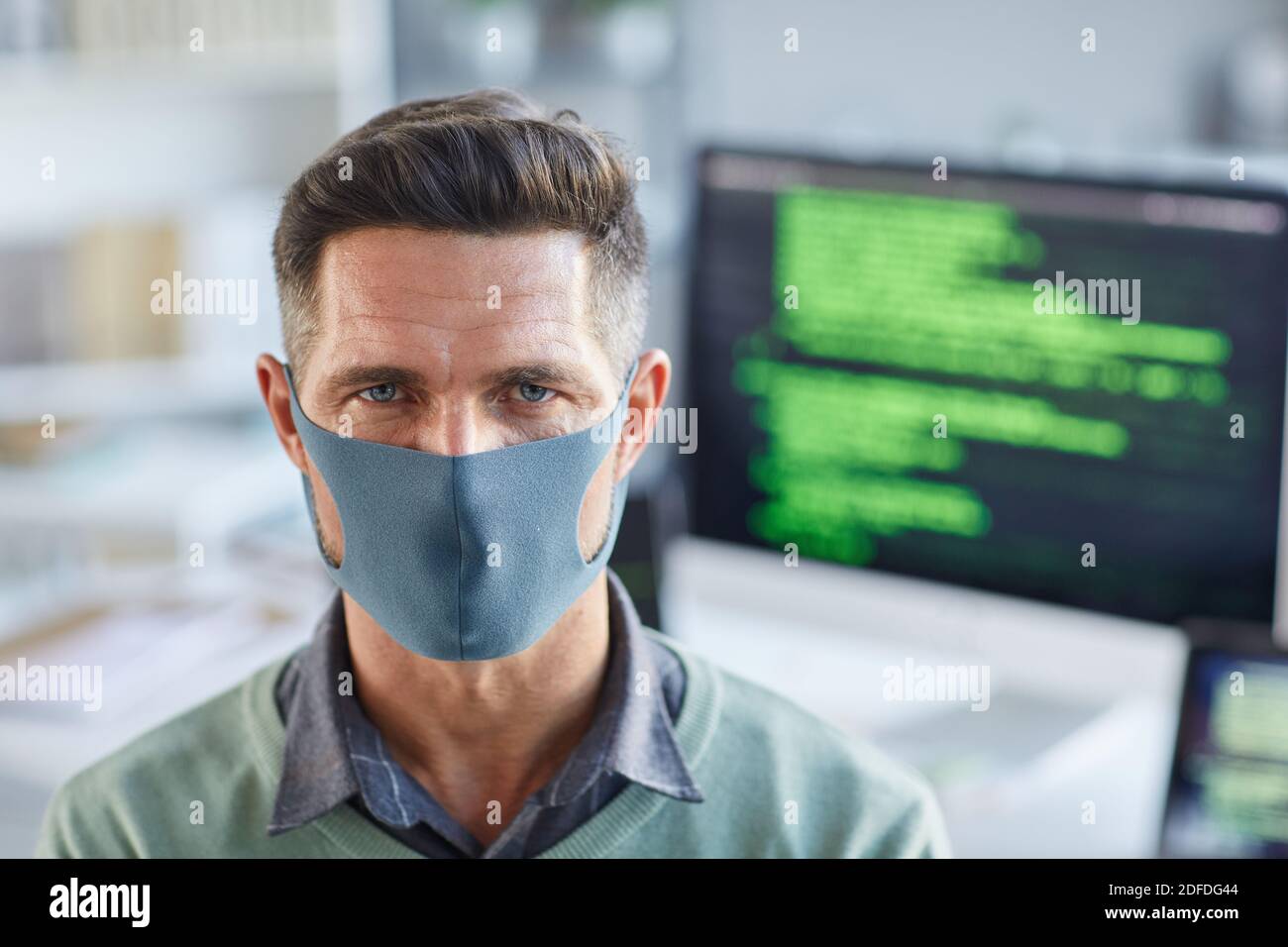 Portrait of young man in protective mask looking at camera while working at office Stock Photo