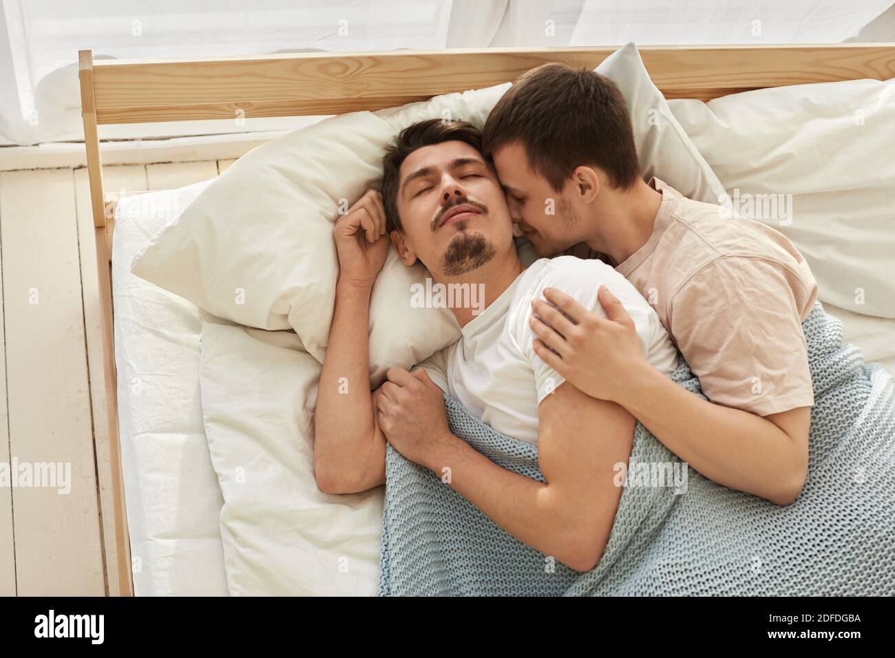 Happy gay couple lying on bed at home view from above Stock Photo