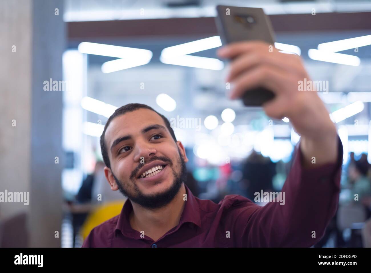 Smiling young african  man using smartphone in a modern cafe Stock Photo