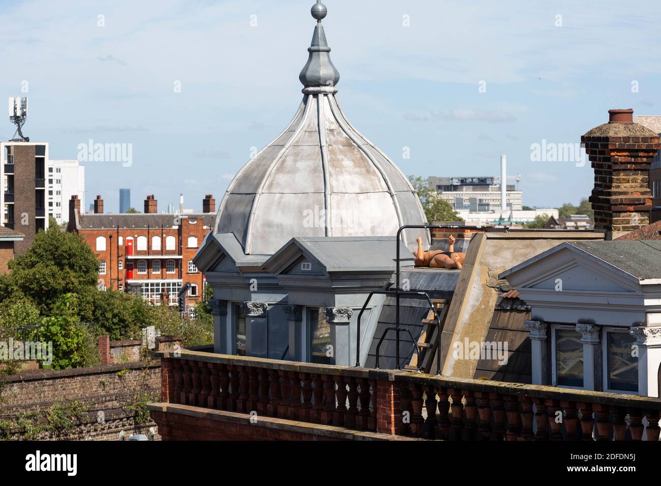 A person sunbathing on a roof on Electric Avenue, Brixton, London Stock Photo