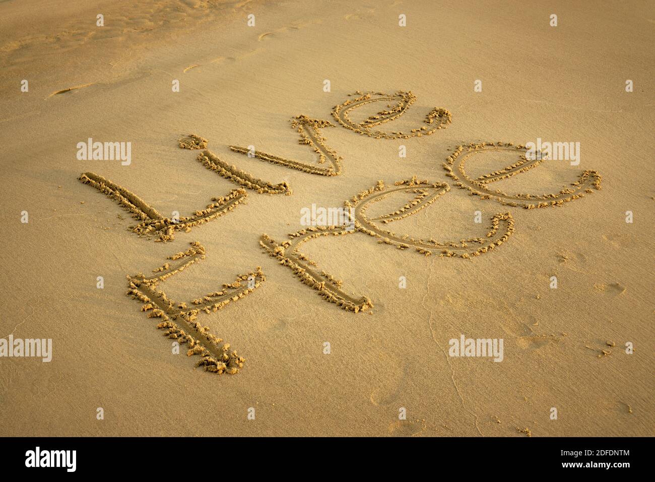 Live Free Written on Beach Sand. Freedom and Life Exploration Concept. Stock Photo