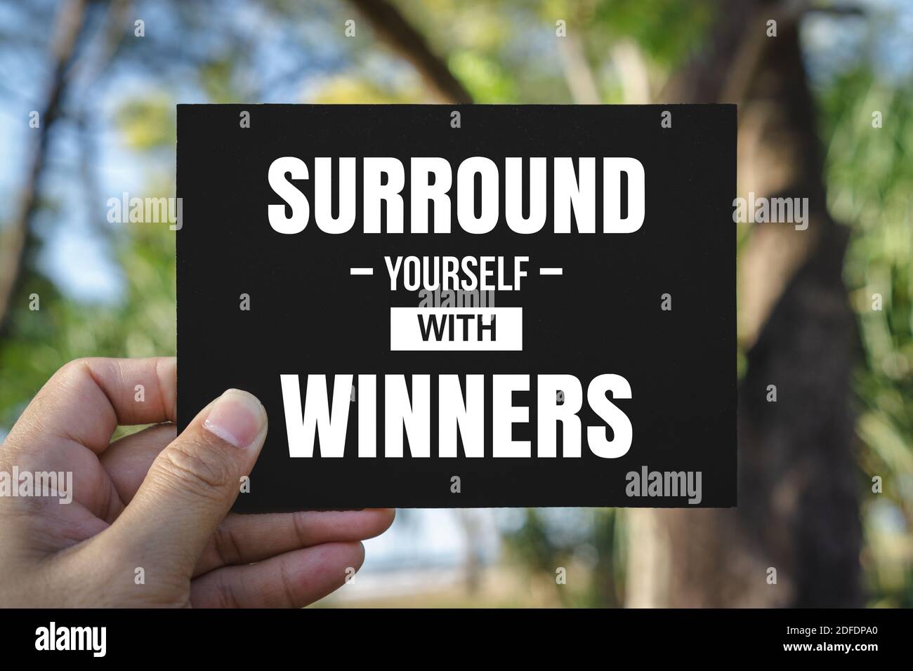 Inspirational and Motivational Quote. Hand Holding Black Paper. Surround Yourself With Winners. Stock Photo