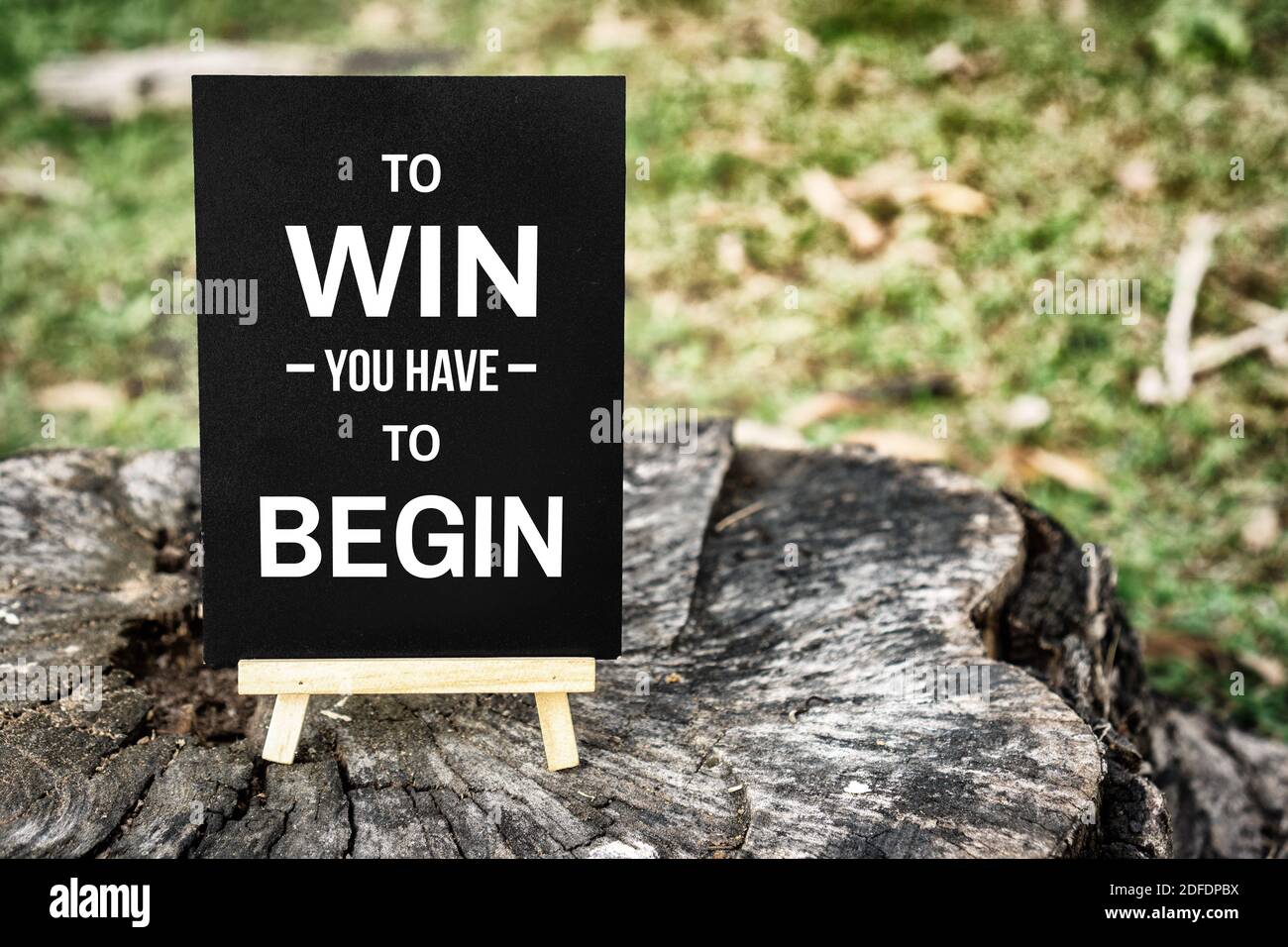 Inspirational and Motivational Quote. To Win You Have To Begin. Mini Blackboard on Wood. Stock Photo