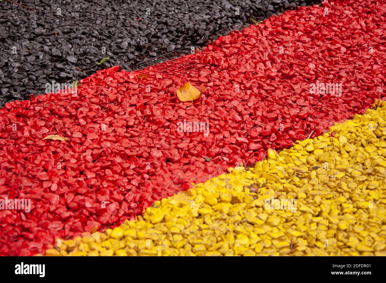 Fine gravel painted in dark grey, red and yellow Stock Photo