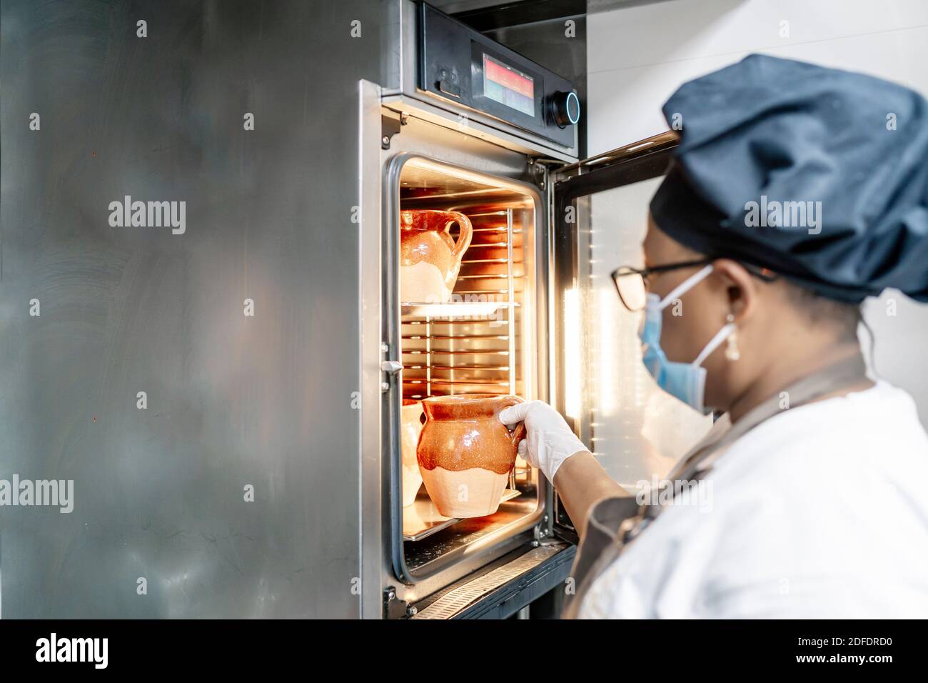 cook putting dishes in the oven Stock Photo Alamy