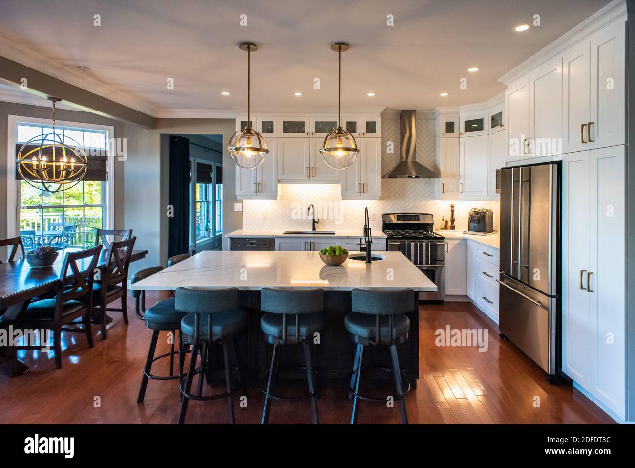 Modern kitchen with white cupboards, dark island and gold accents. Stock Photo