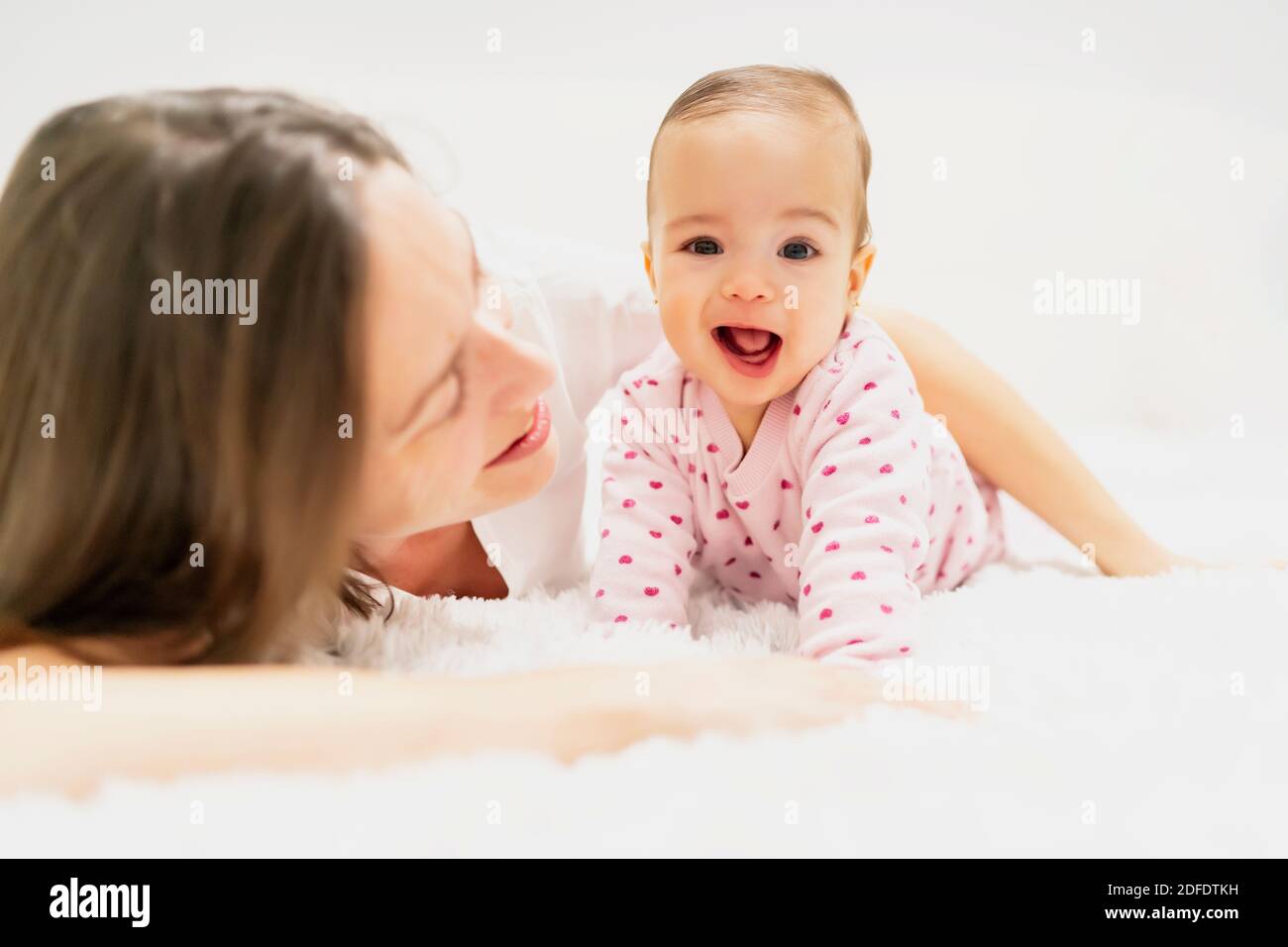 mother lying with her little daughter in bed Stock Photo
