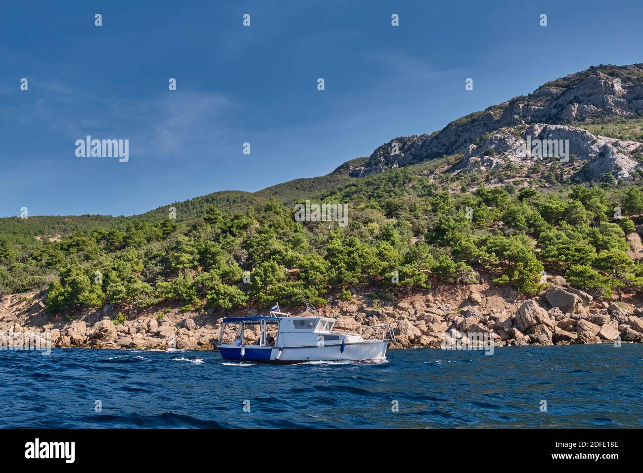 Seascape. The boat sails alongside the rocky coast in the direction of Cape Aya. Balaklava environs, Sevastopol, Crimean peninsula, Russia. Stock Photo